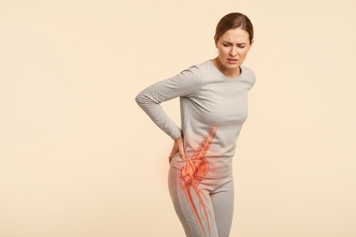 Person experiencing sciatica pain with medical illustration showing sciatic nerve pathway in coral and cream brand colors